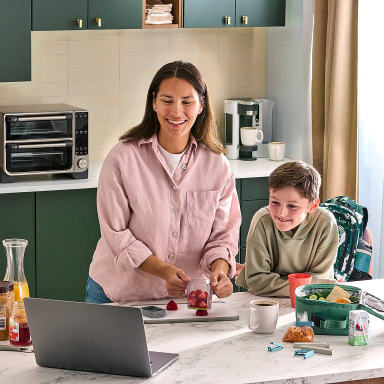 consultant with a child cooking a meal while looking at a laptop computer