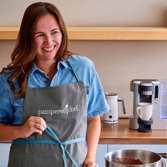 a consultant wearing a pampered chef apron working in a kitchen
