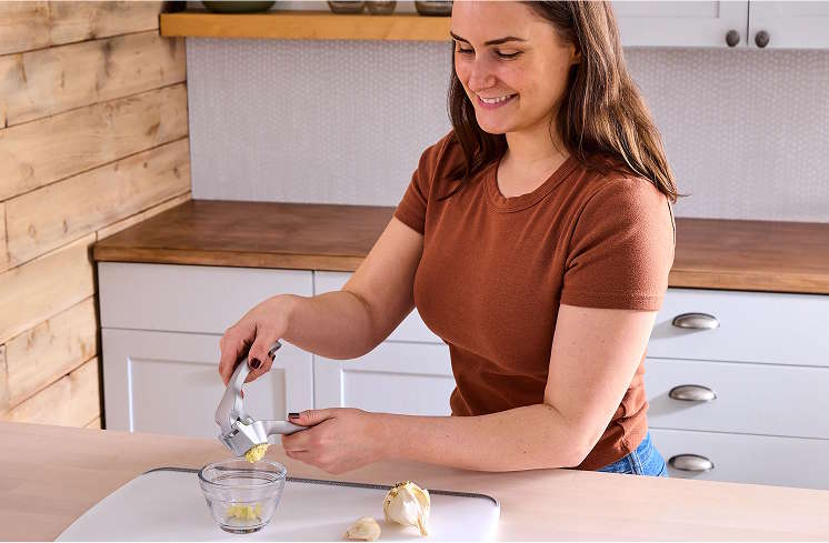 A party guest using the garlic press